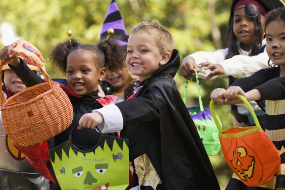 Kids in Halloween costumes with candy baskets.