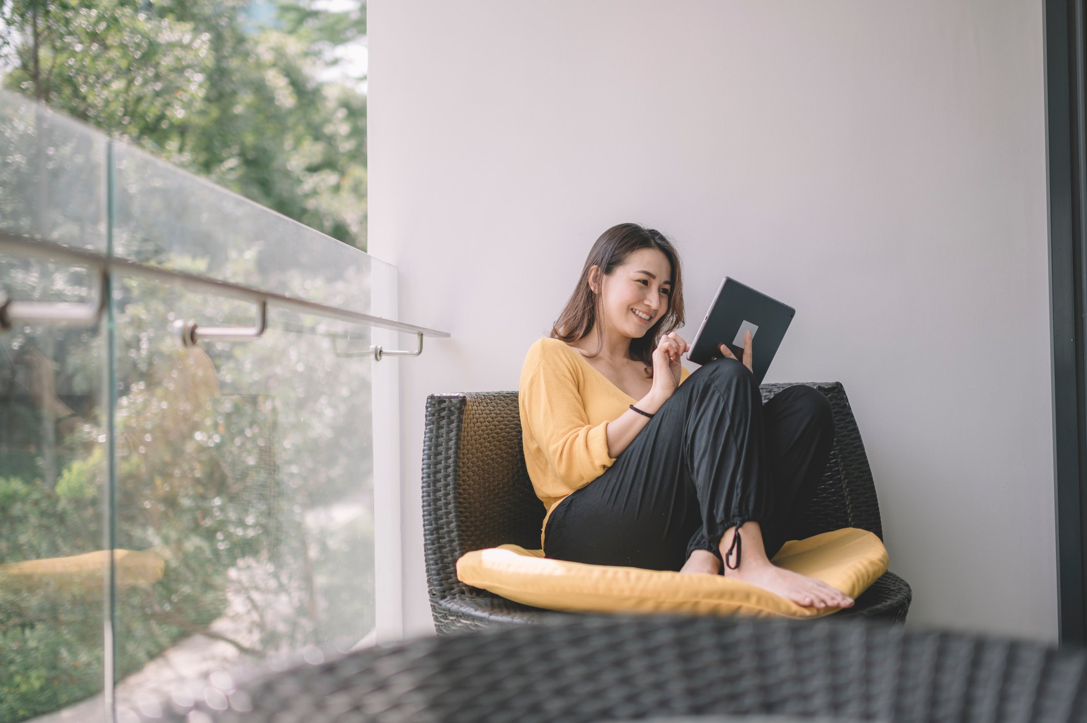 A person looking at their tablet on an outdoor balcony.