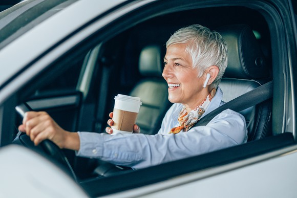 A woman drinking coffee in her car.