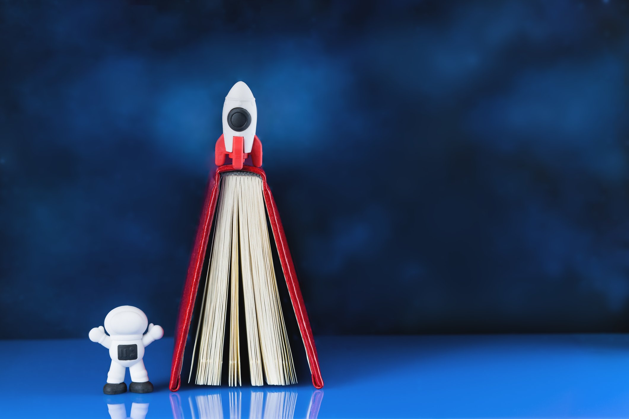 A book, an astronaut toy, and a miniature rocket.