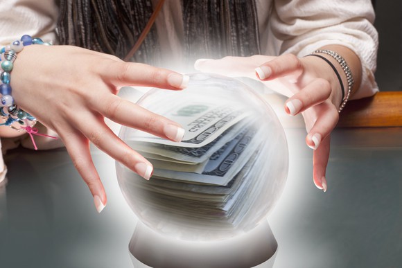 Hands around crystal ball with money in it.