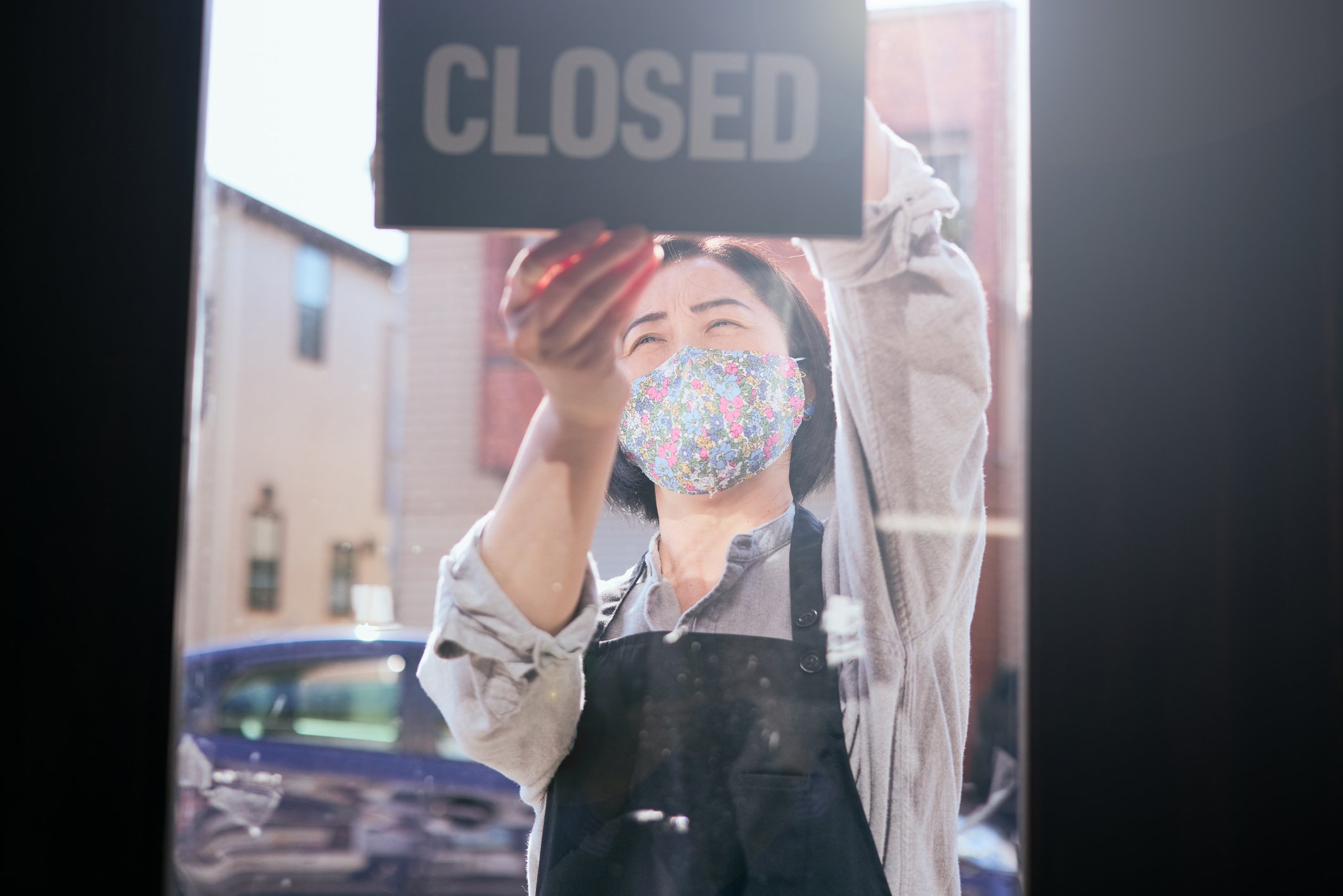 A person is hanging a "closed" sign on a door. 