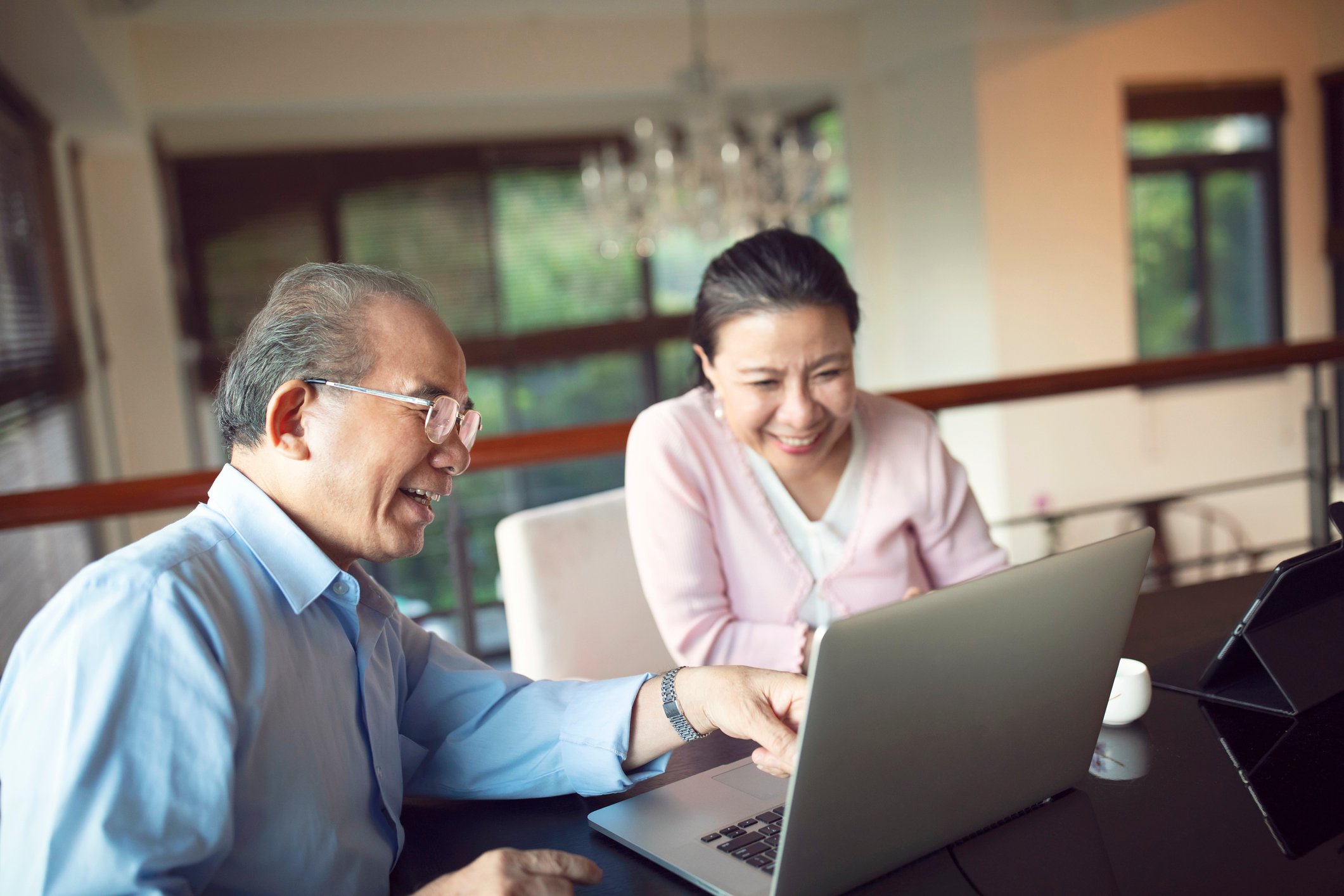 Two smiling people looking at a laptop.