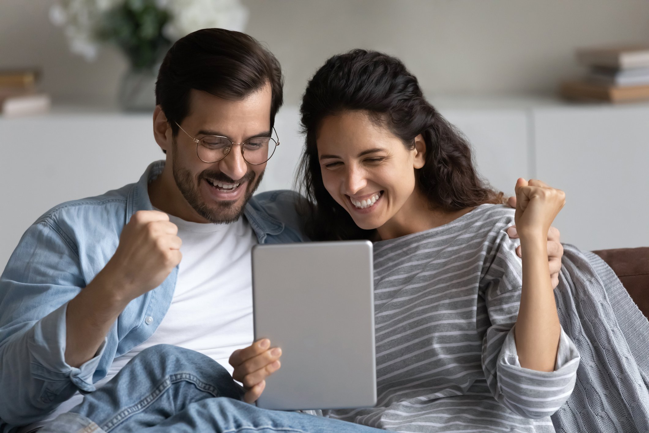 Two smiling people looking at a touchscreen tablet.