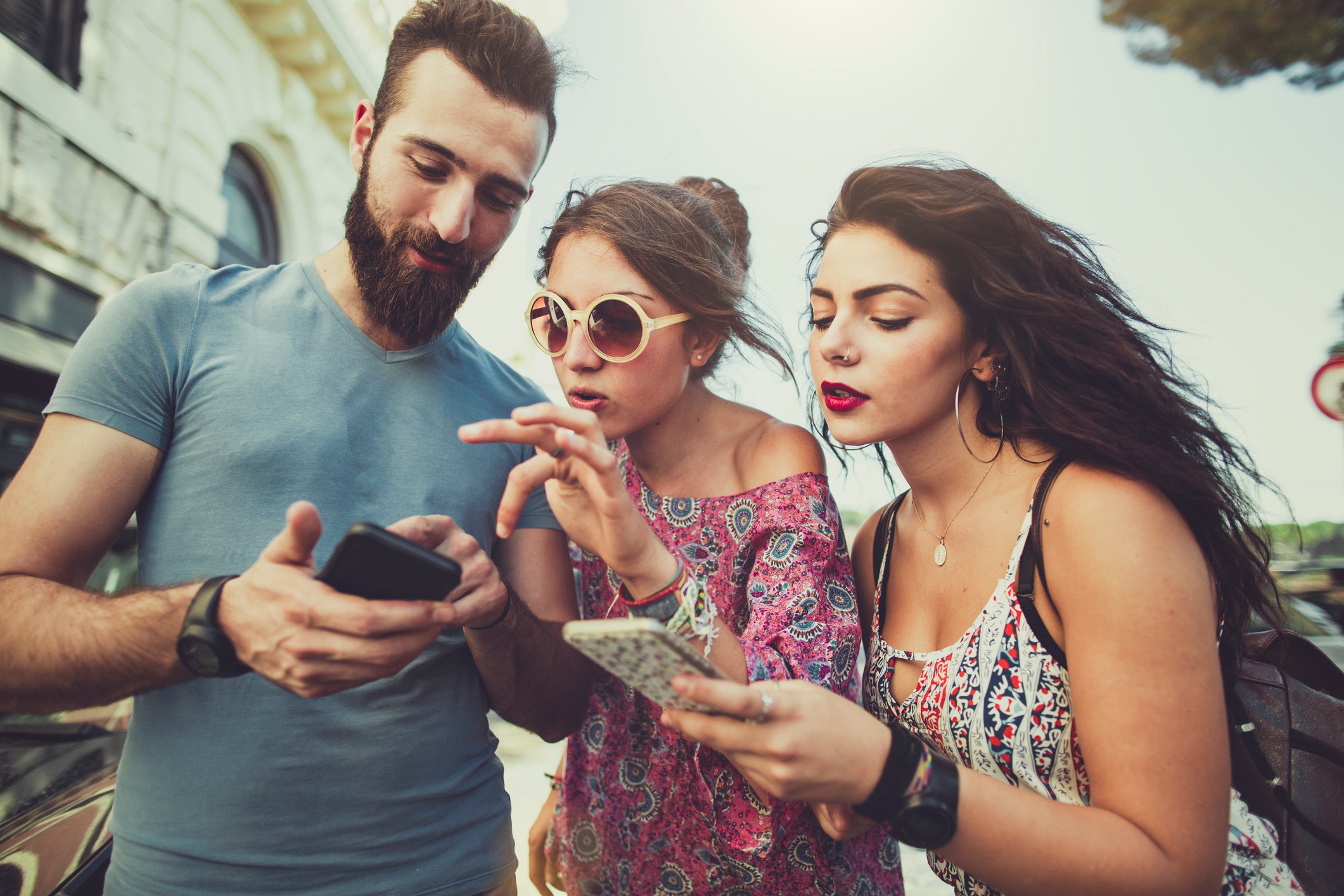 Group of young people crowding around a smartphone.