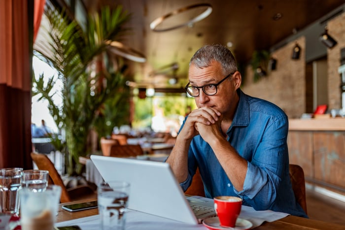 Older person looking at a laptop feeling worried