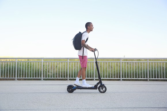 Person riding a scooter on a paved path.