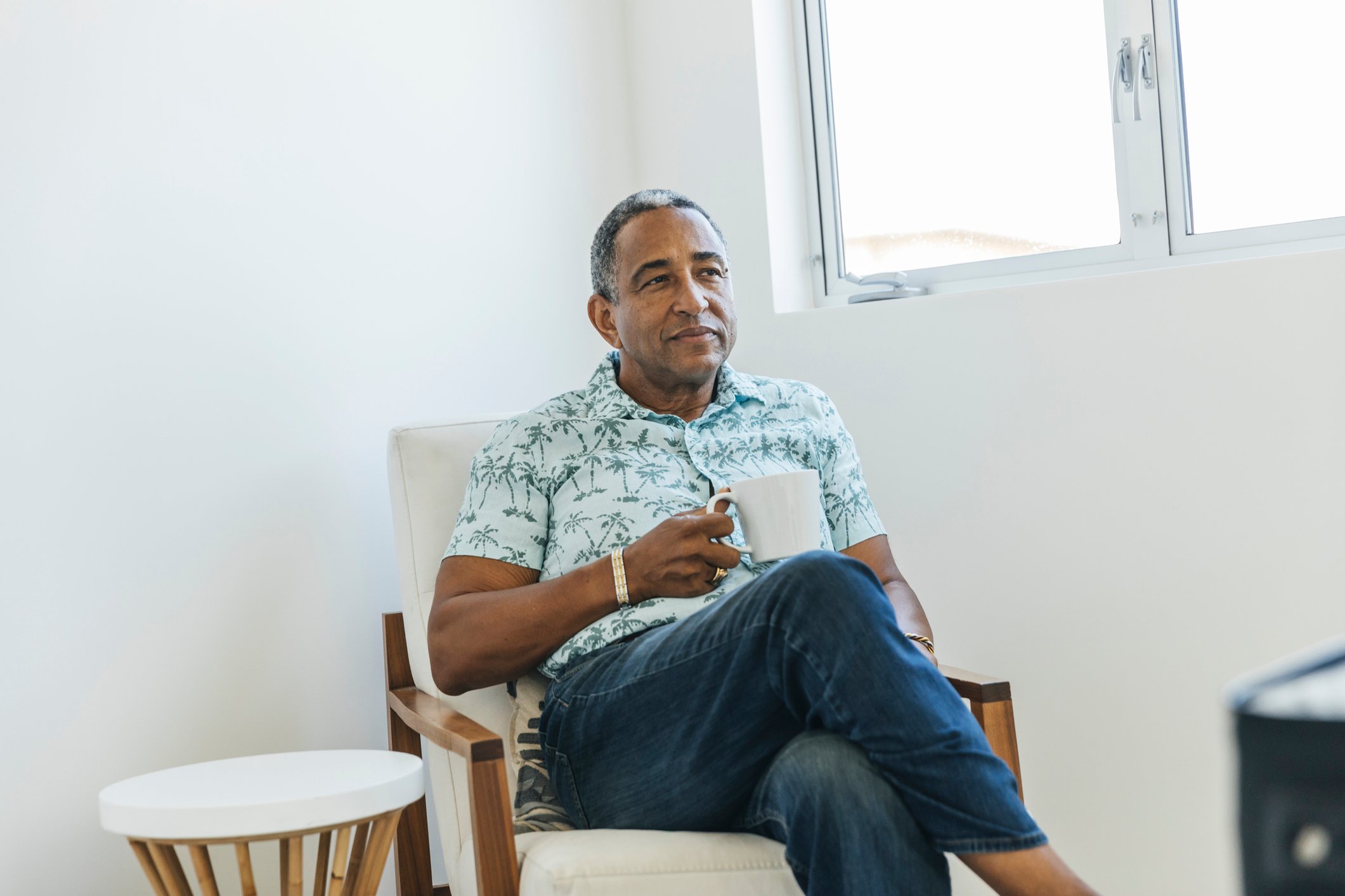 Person holding a cup of coffee and looking thoughtful.