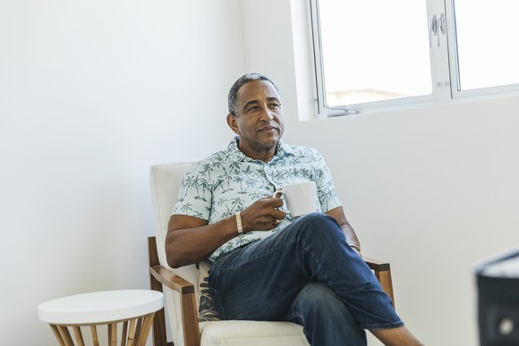 Person holding a cup of coffee and looking thoughtful.