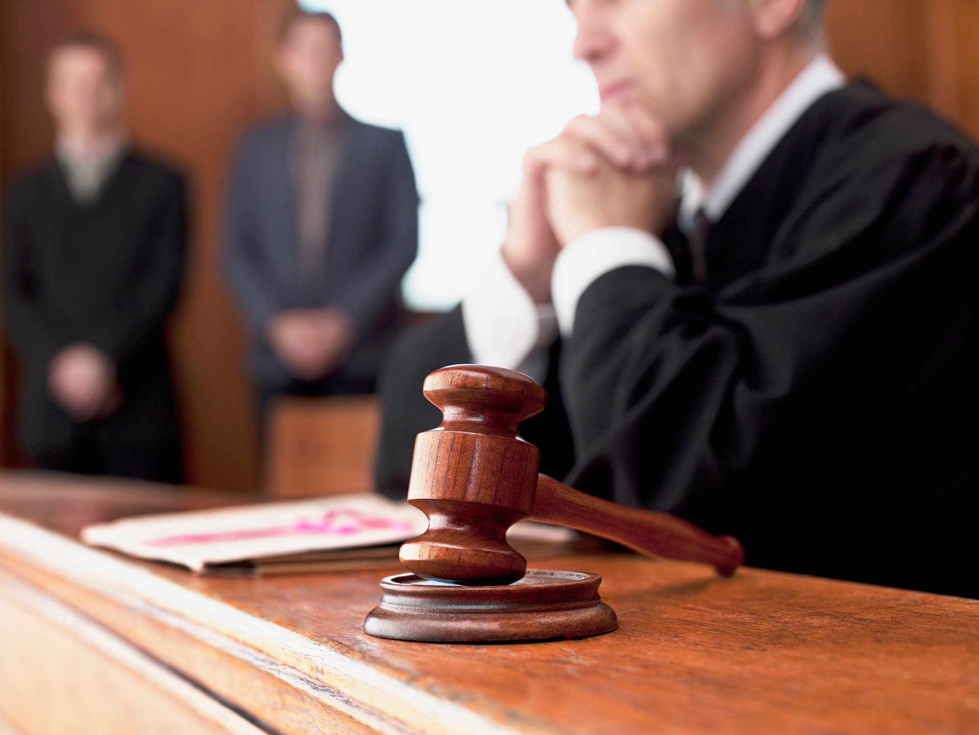 A judge next to a gavel with two people in the background.