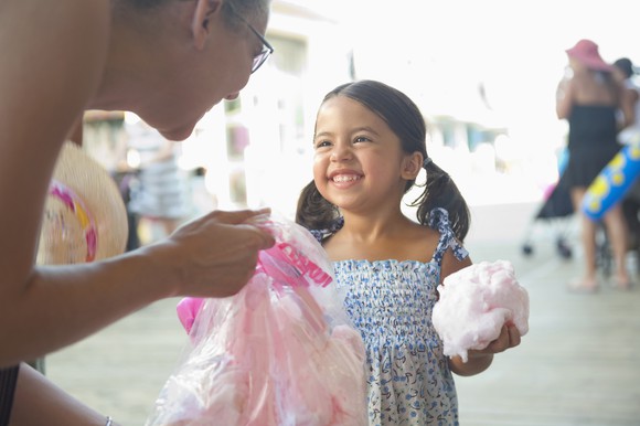 A child and adult smiling over cotton candy.