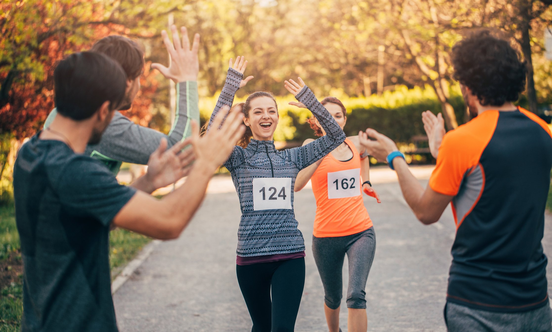 Runners finishing race with friends cheering.