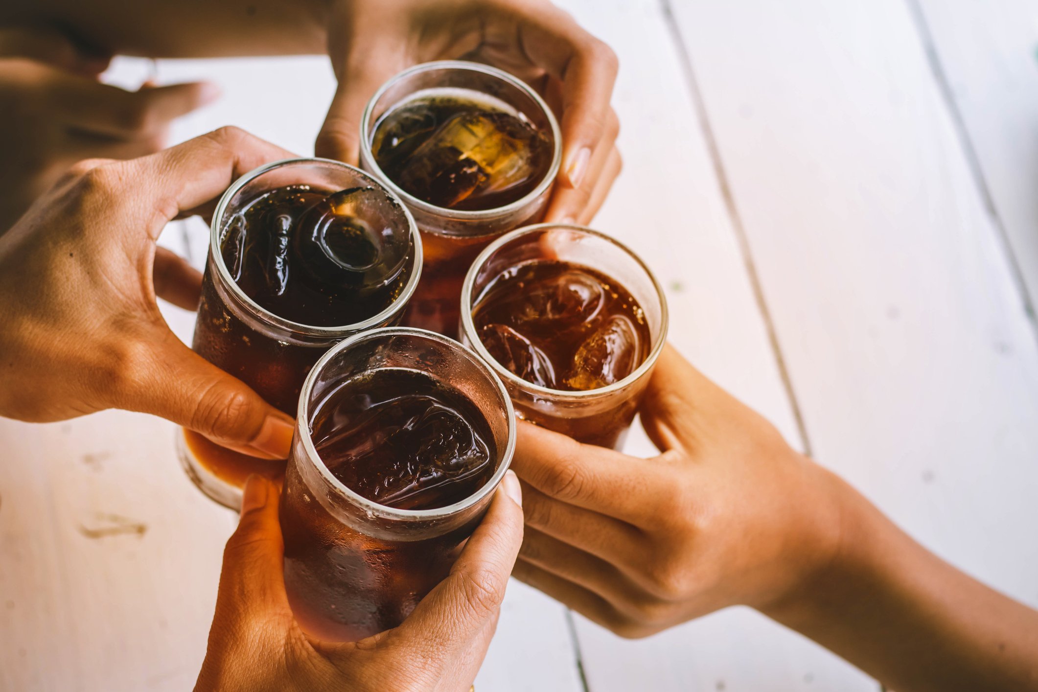 A group of people toast their cola-filled glasses.