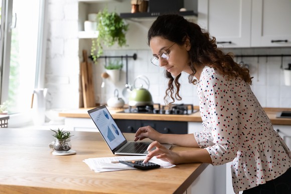 Person typing on computer and calculator.