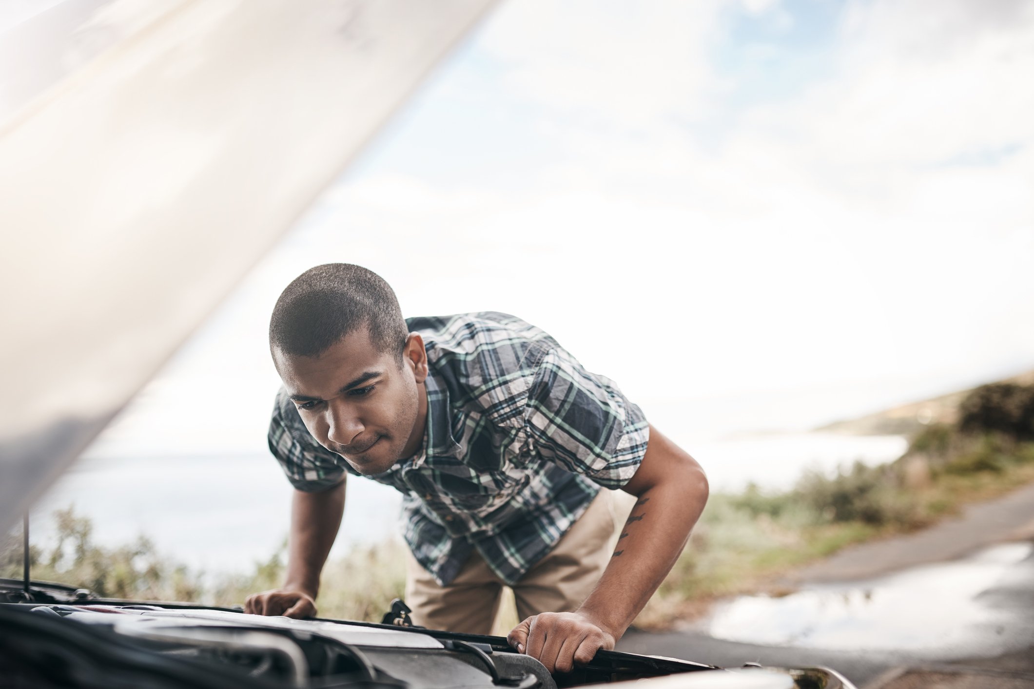 A person looking under the hood of a car.