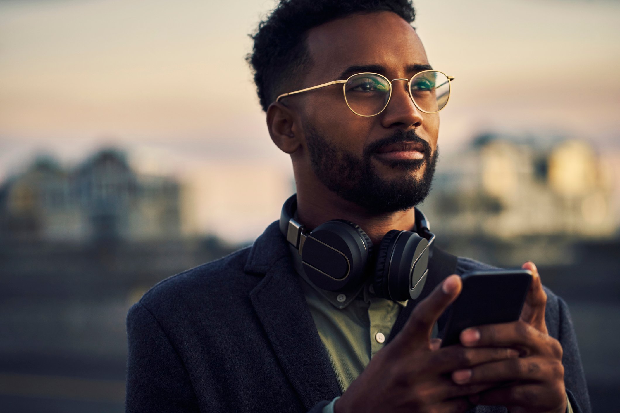Businessperson outside with mobile device and headphones.