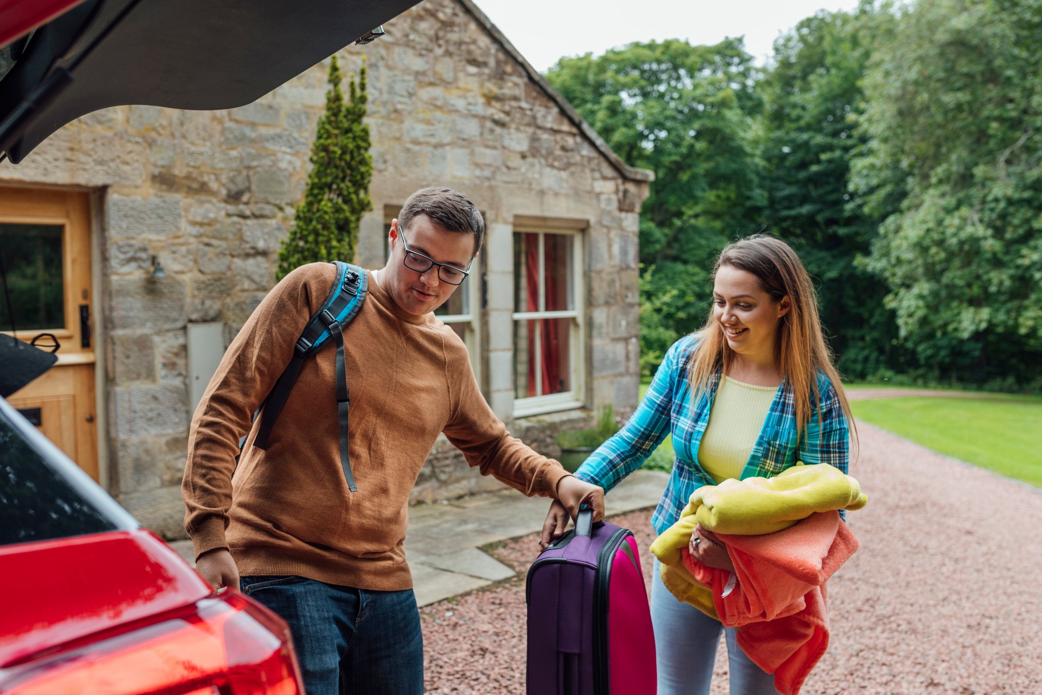 A couple loading luggage in their car.
