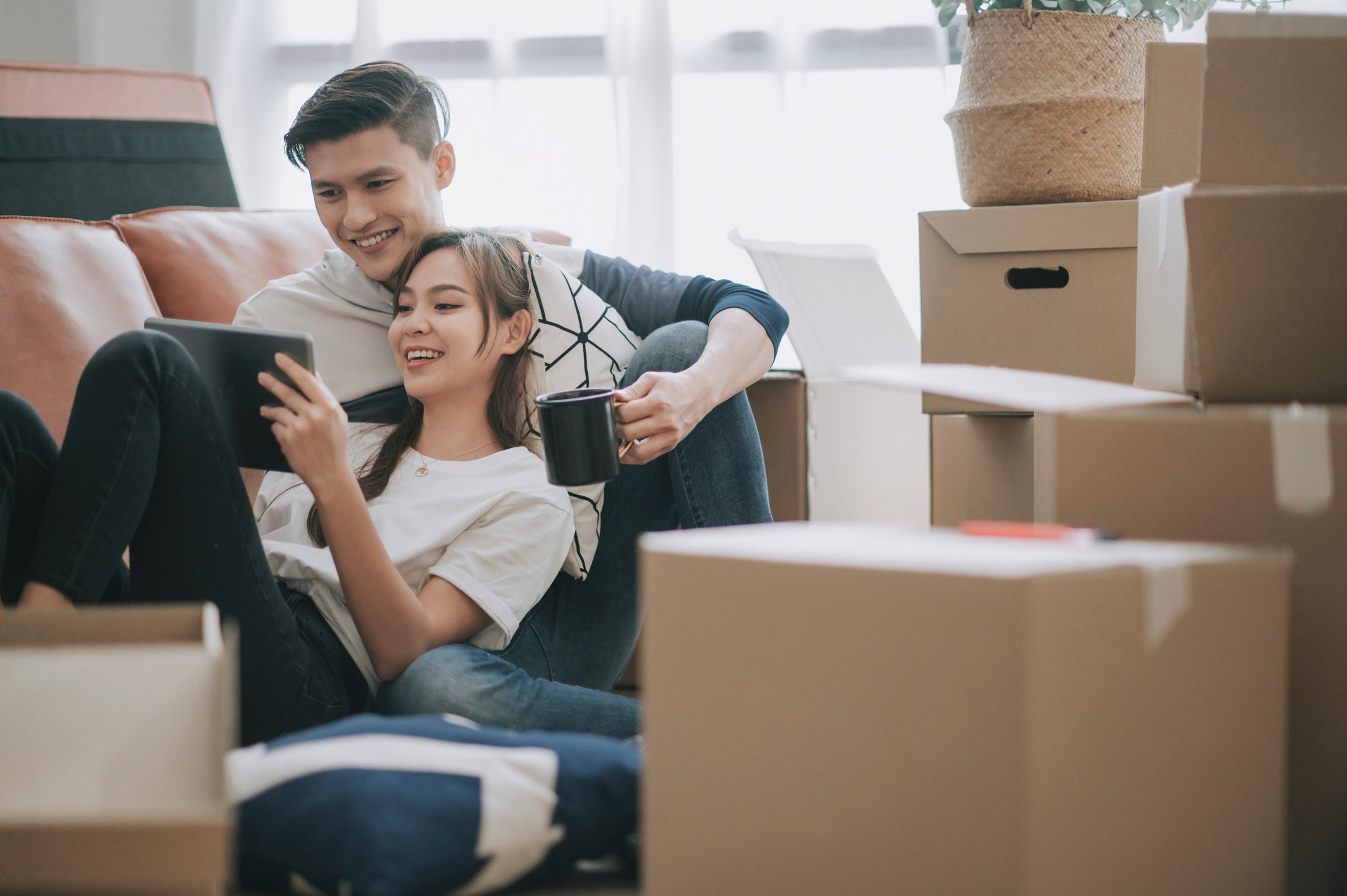 A couple sitting in their new house surrounded by boxes