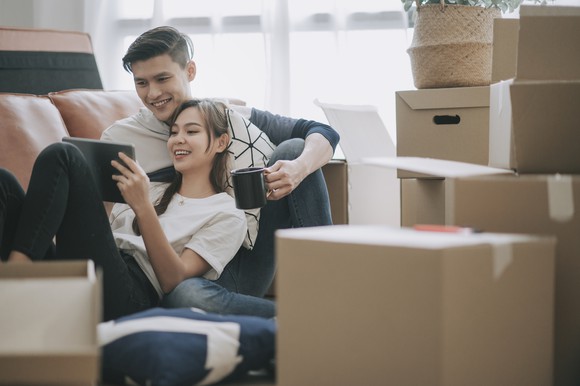 A couple sitting in their new house surrounded by boxes