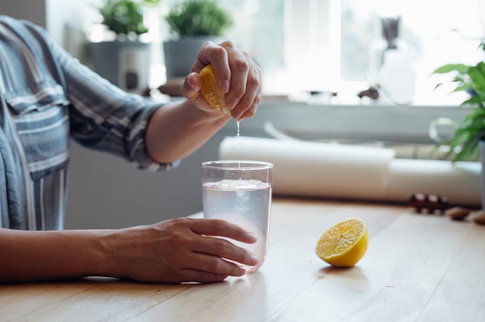 Squeezing lemon juice into a glass of lemonade.