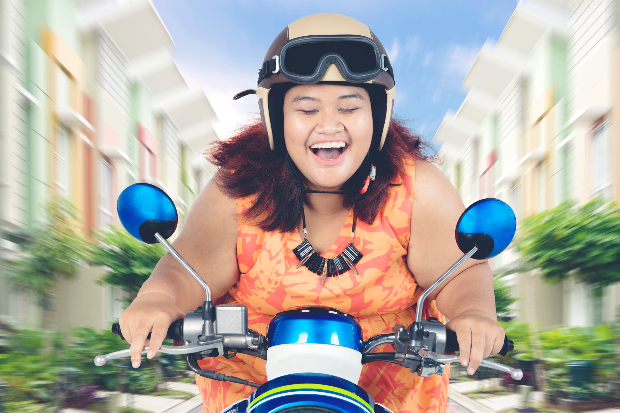 A person is smiling broadly, riding a motorcycle.