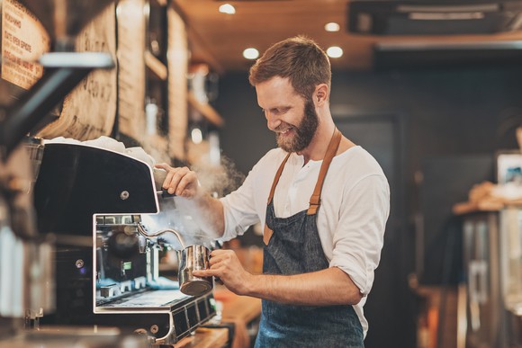 Smiling barista making a cappuccino.