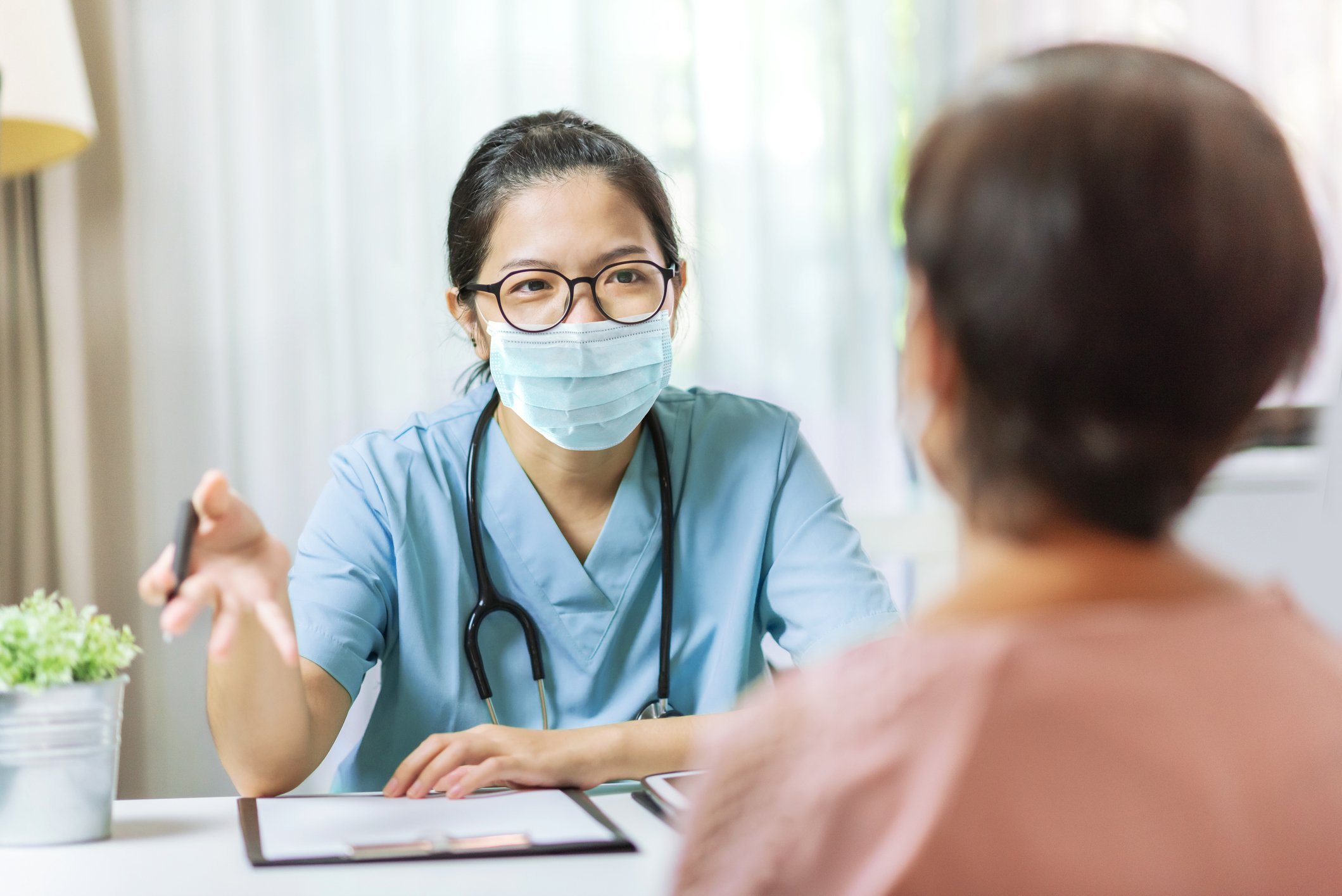 Masked healthcare professional reviewing paperwork with a patient.