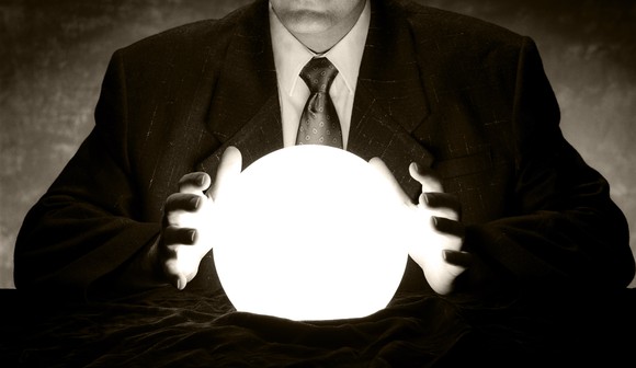 A person wearing a suit has their hands on either side of a glowing ball.