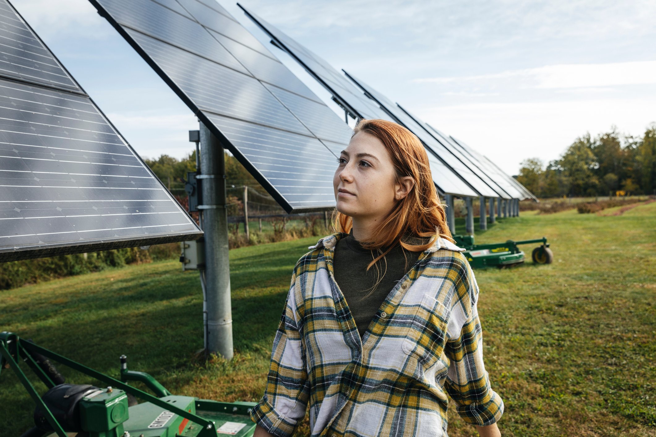 Young woman looking at solar panels on farm.