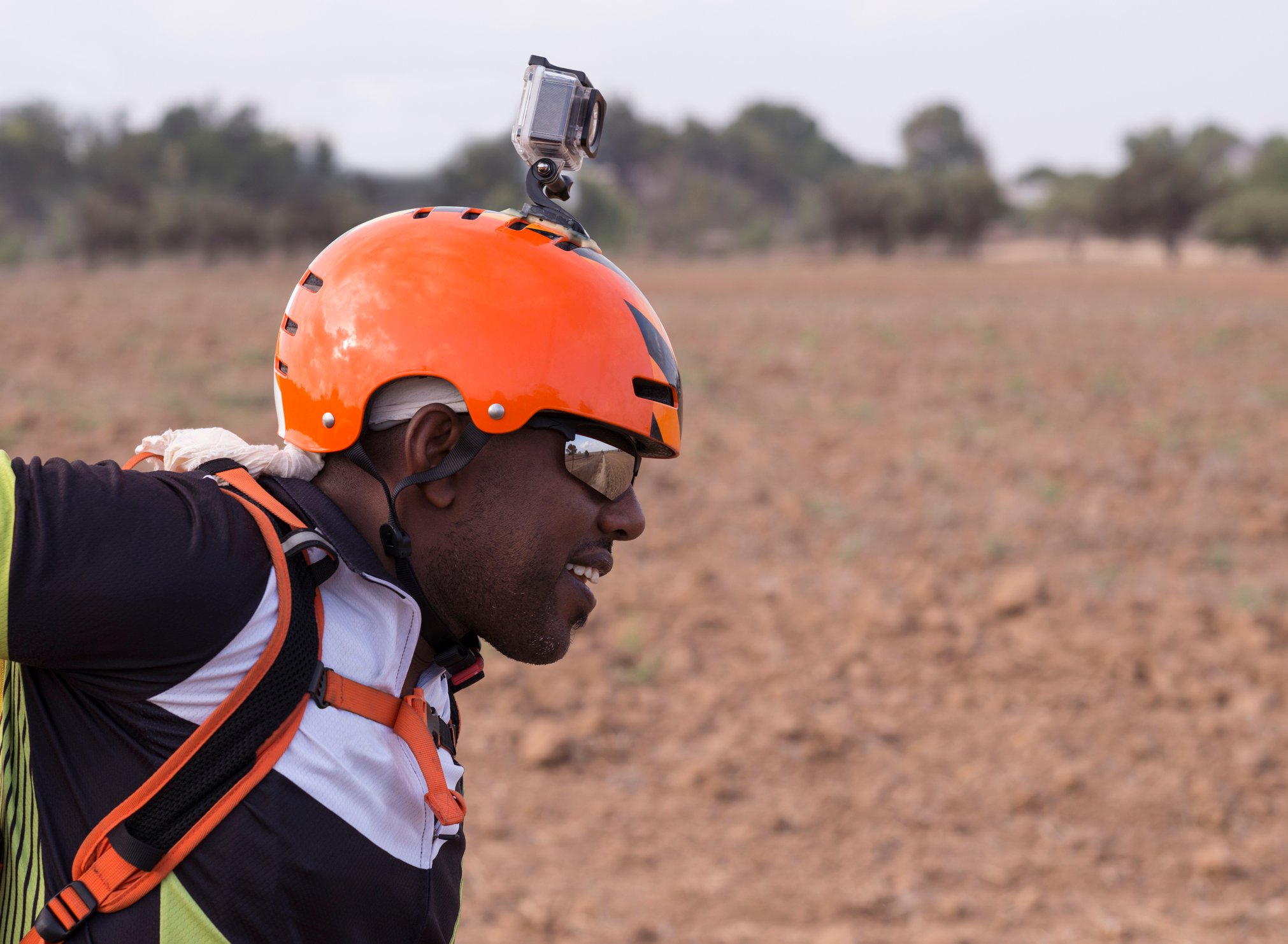 A person wearing an orange helmet with an action camera attached to record activity.