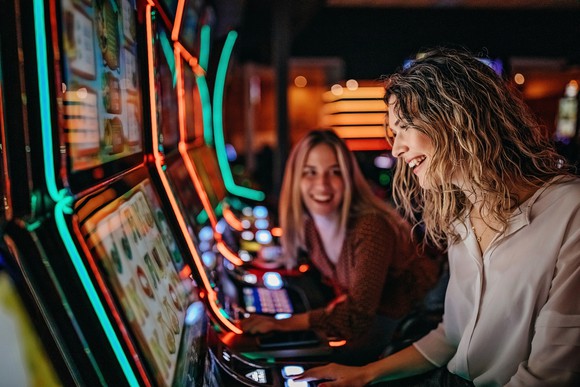 Two people playing on slot machines.
