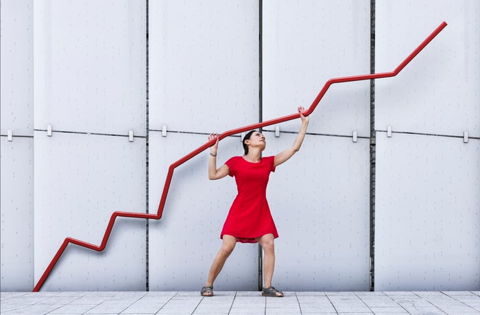 A person standing under a chart with a line that is moving up and to the right.