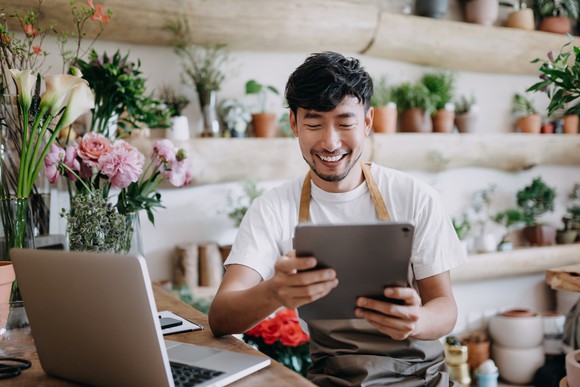 Worker in flower shop reviewing tablet.