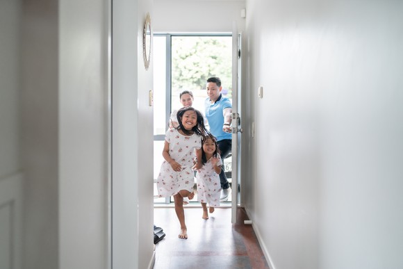 Two children running into their new home with two adults close behind.