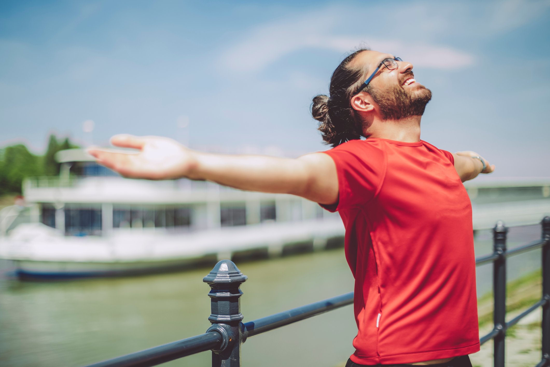 A smiling person is outdoors, with arms outstretched.