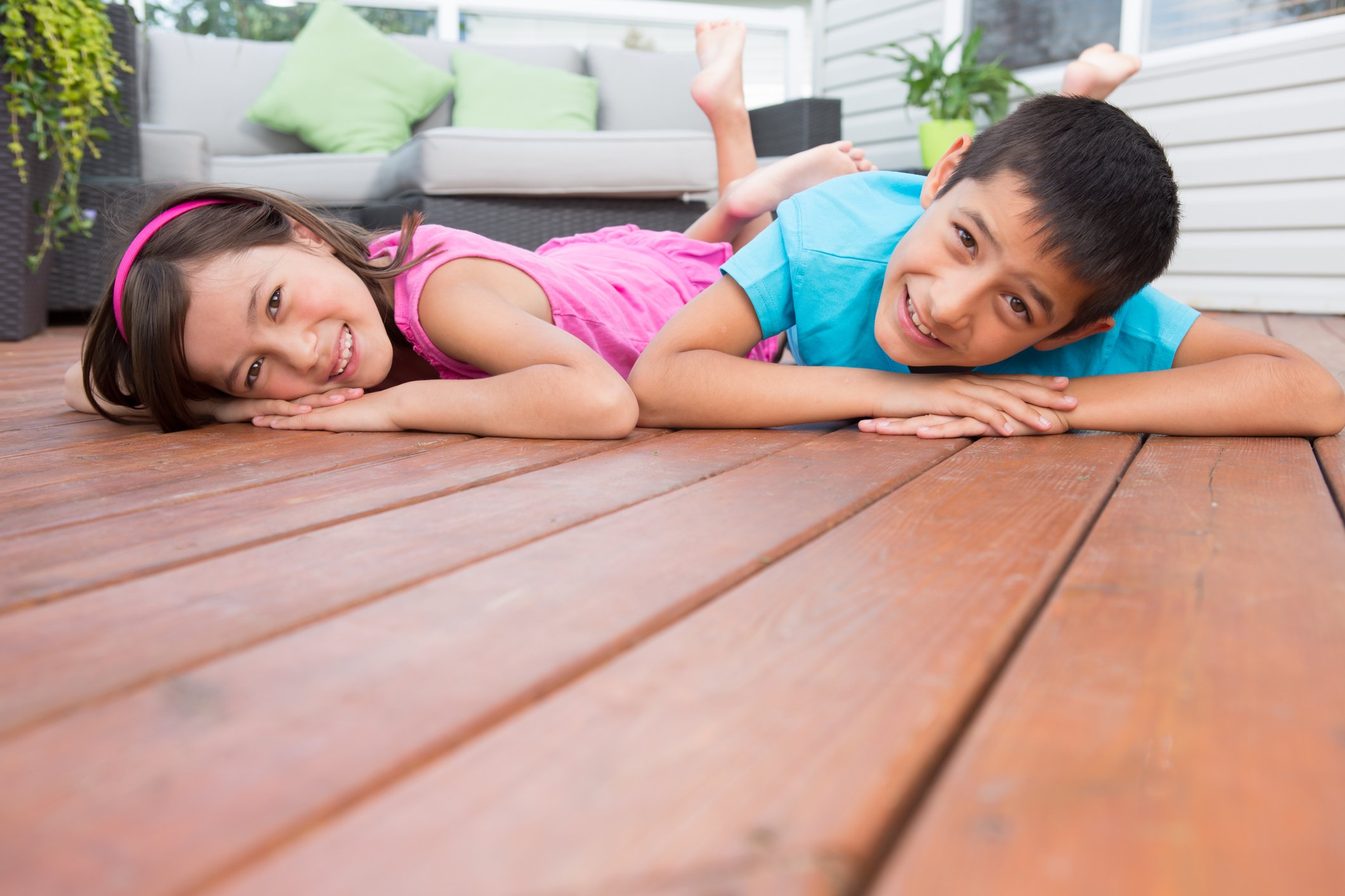 Two children lay on a wood deck.