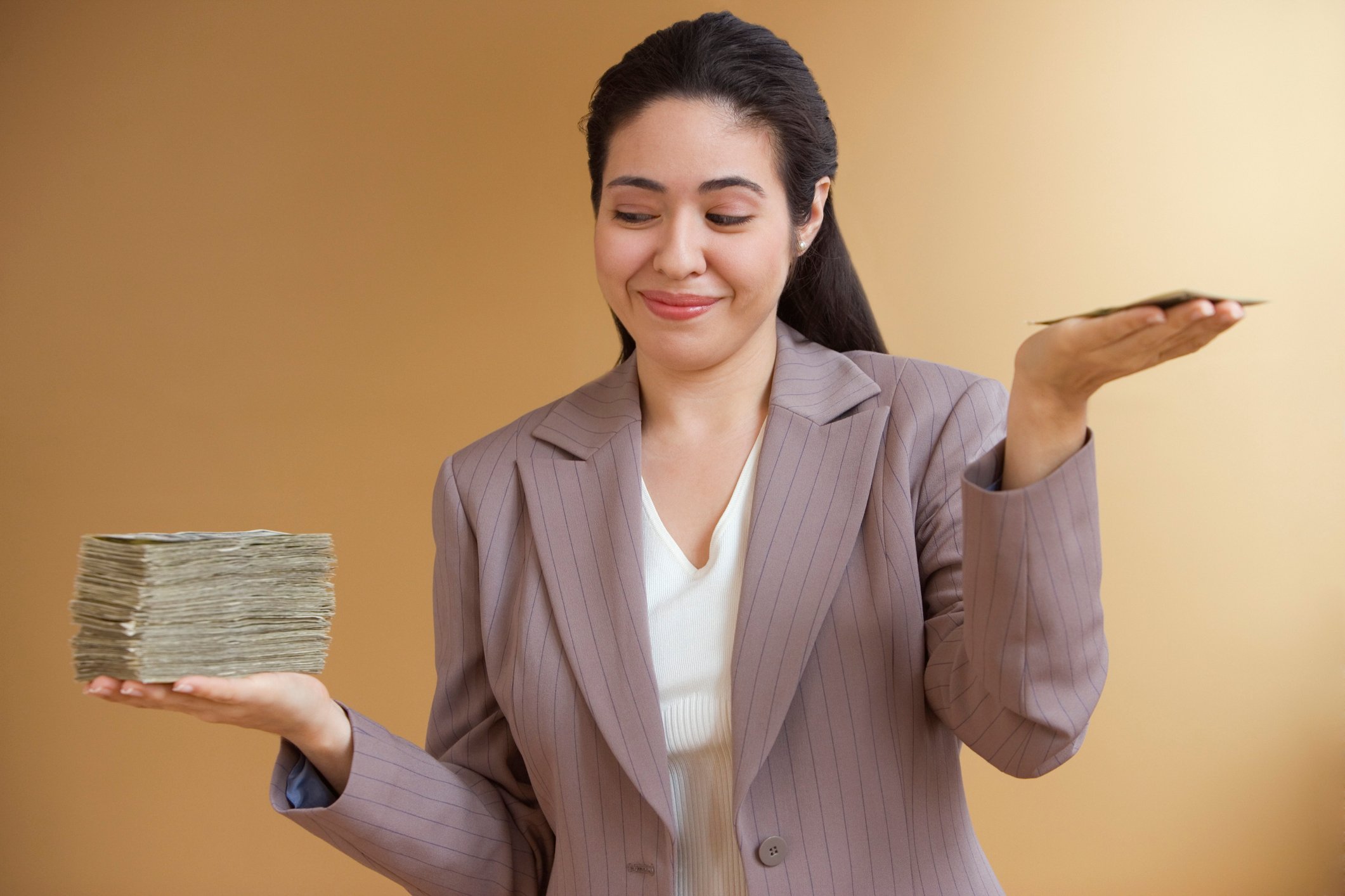 A person holding a big stack of money in one hand and a small stack in the other.