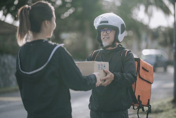 A delivery courier hands off a package to the recipient