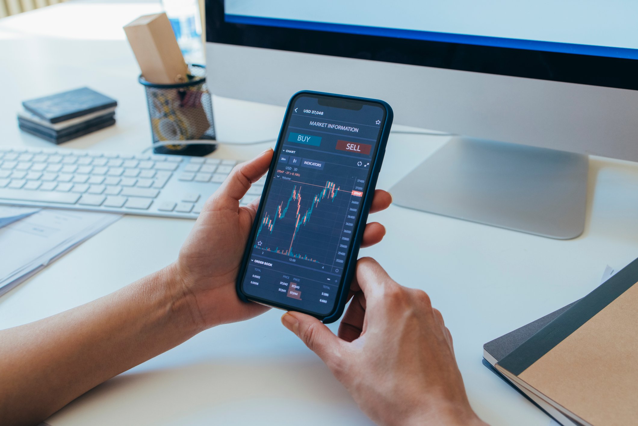 Someone holding their phone and checking investment fluctuations.