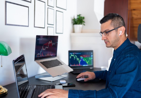 Person in front of three laptops on a desk. 
