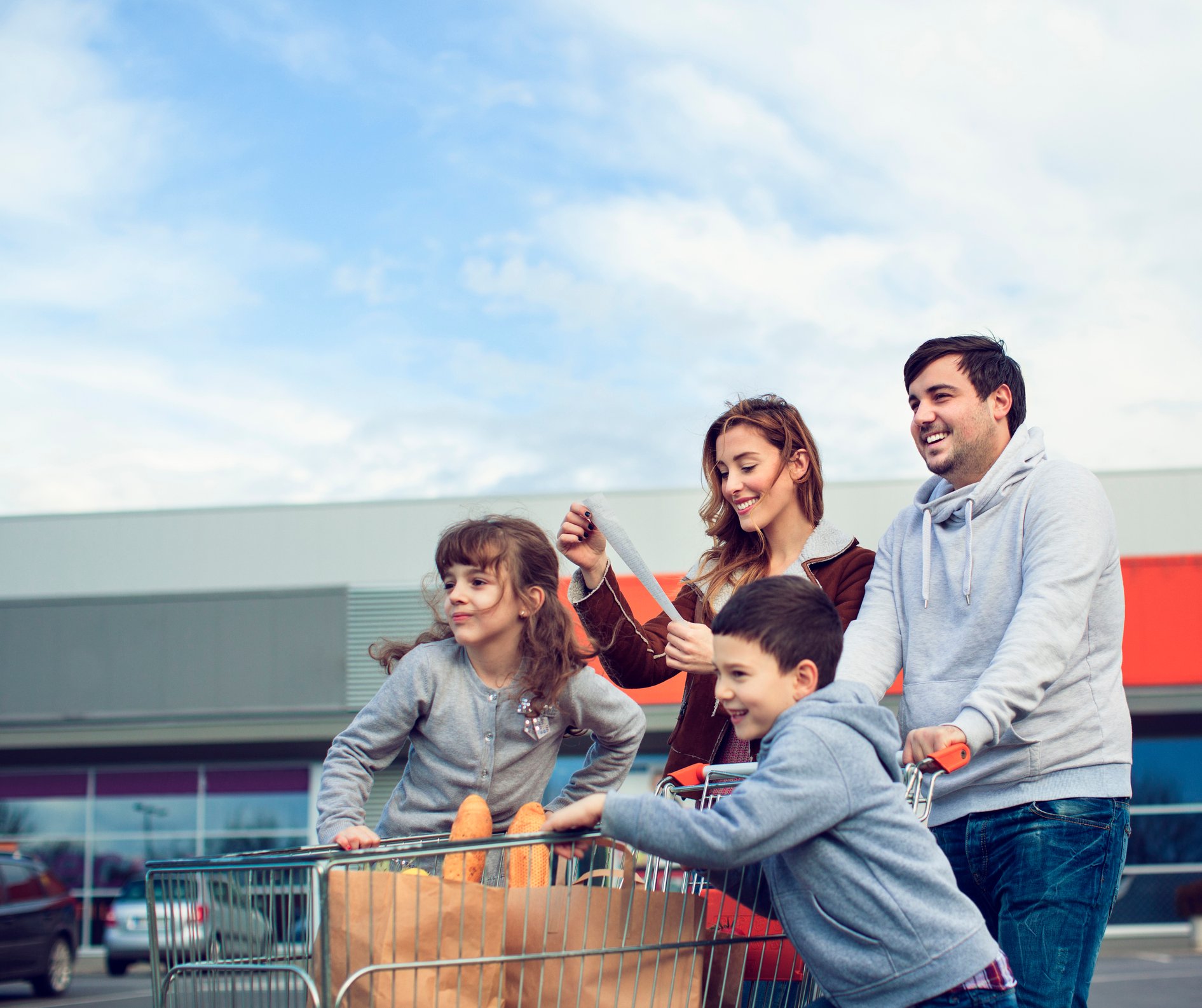 A family with a cart full of items in the parking lot of a store.