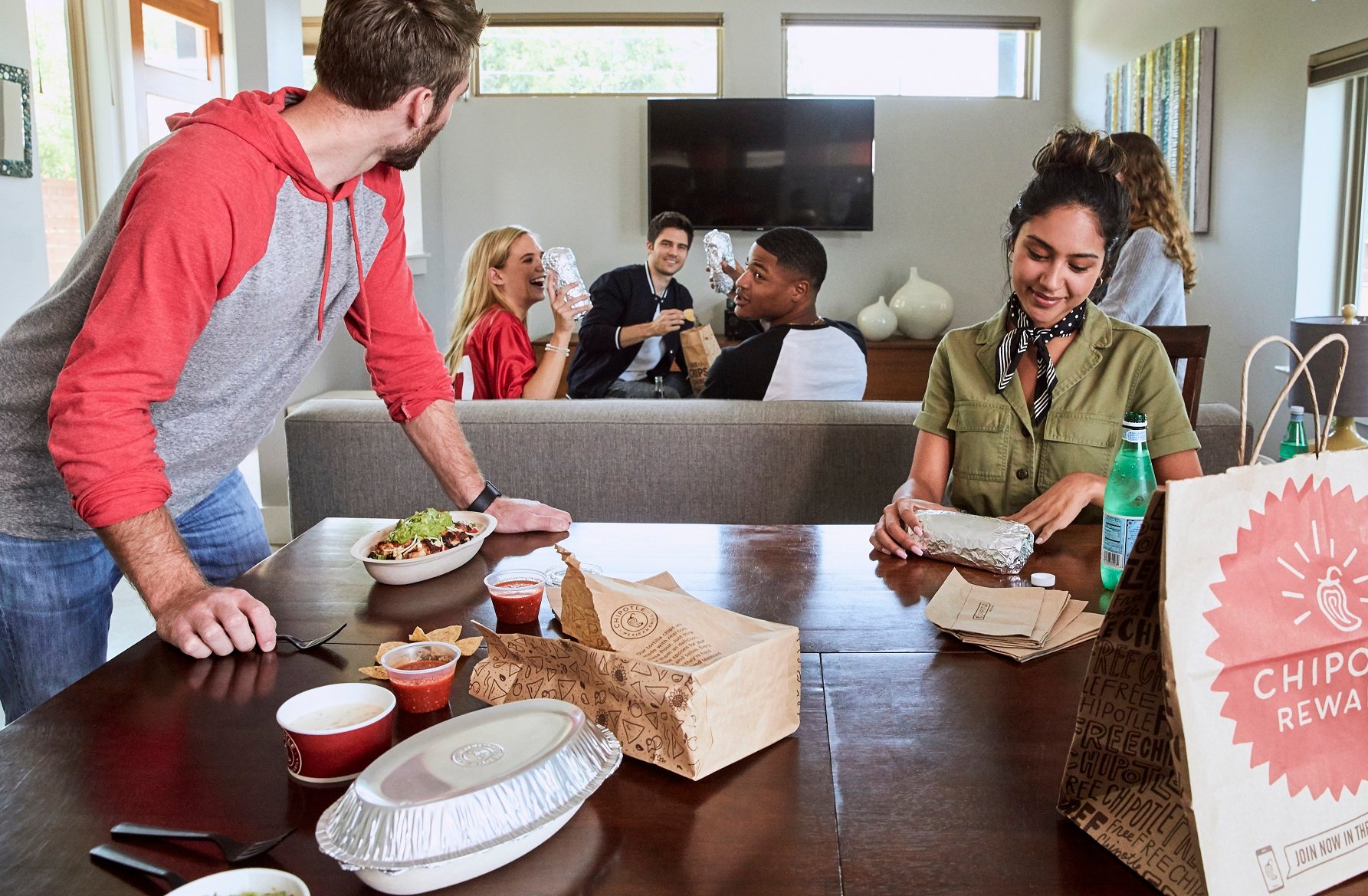 A group of young adults preparing to eat takeout from Chipotle.