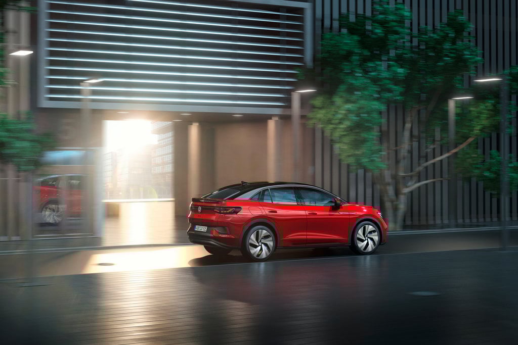 A red Volkswagen electric sedan on a dark street.