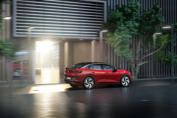 A red Volkswagen electric sedan on a dark street.