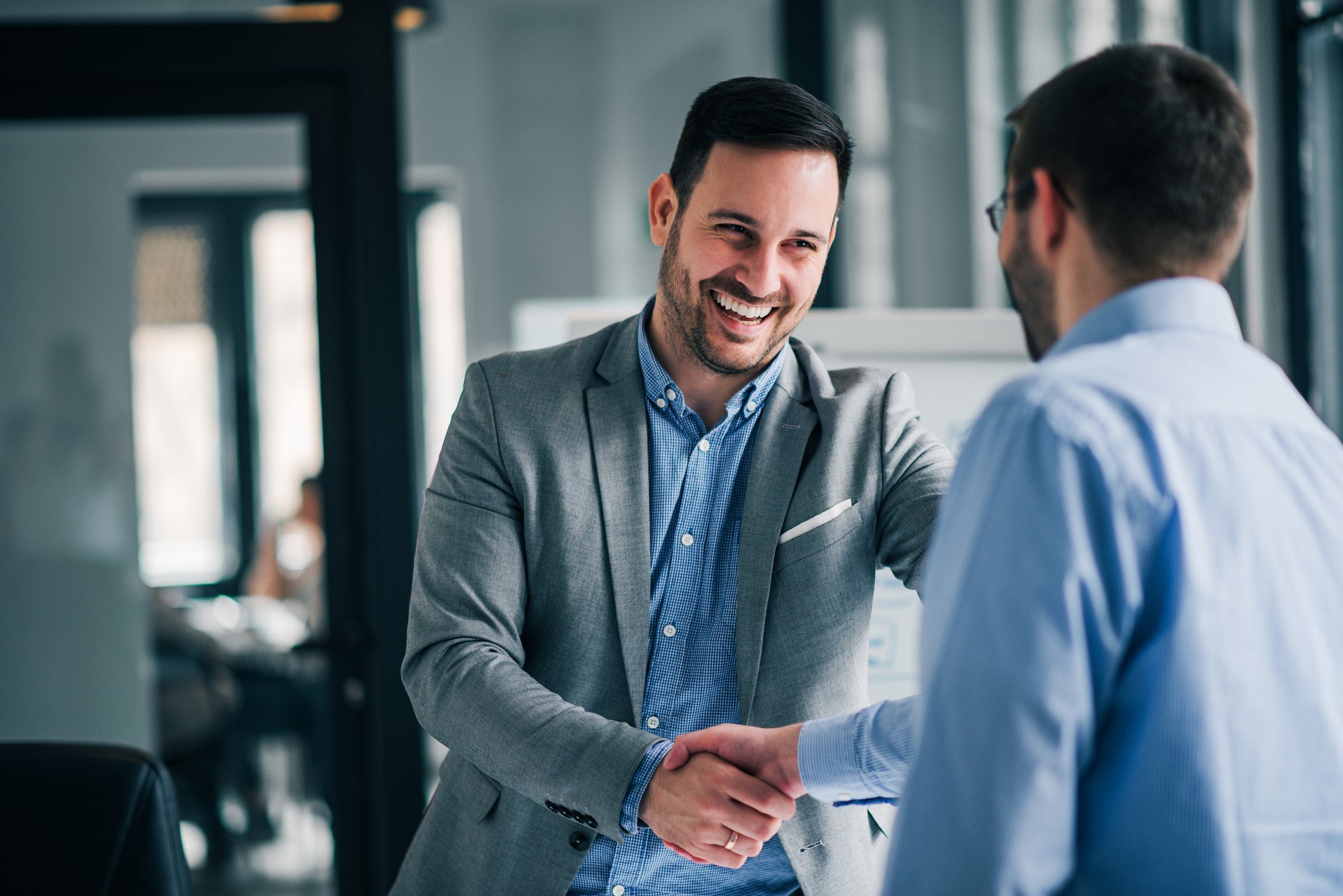 Two people dressed in work attire shake hands.