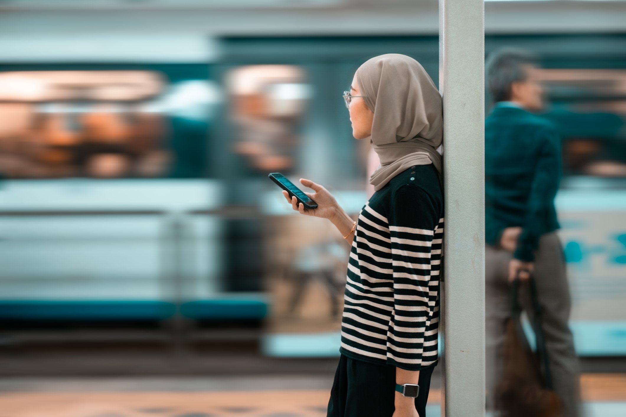 A commuter uses a smartphone while waiting on a train.