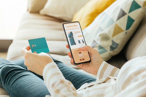 Person buying a dress online with smartphone and credit card.