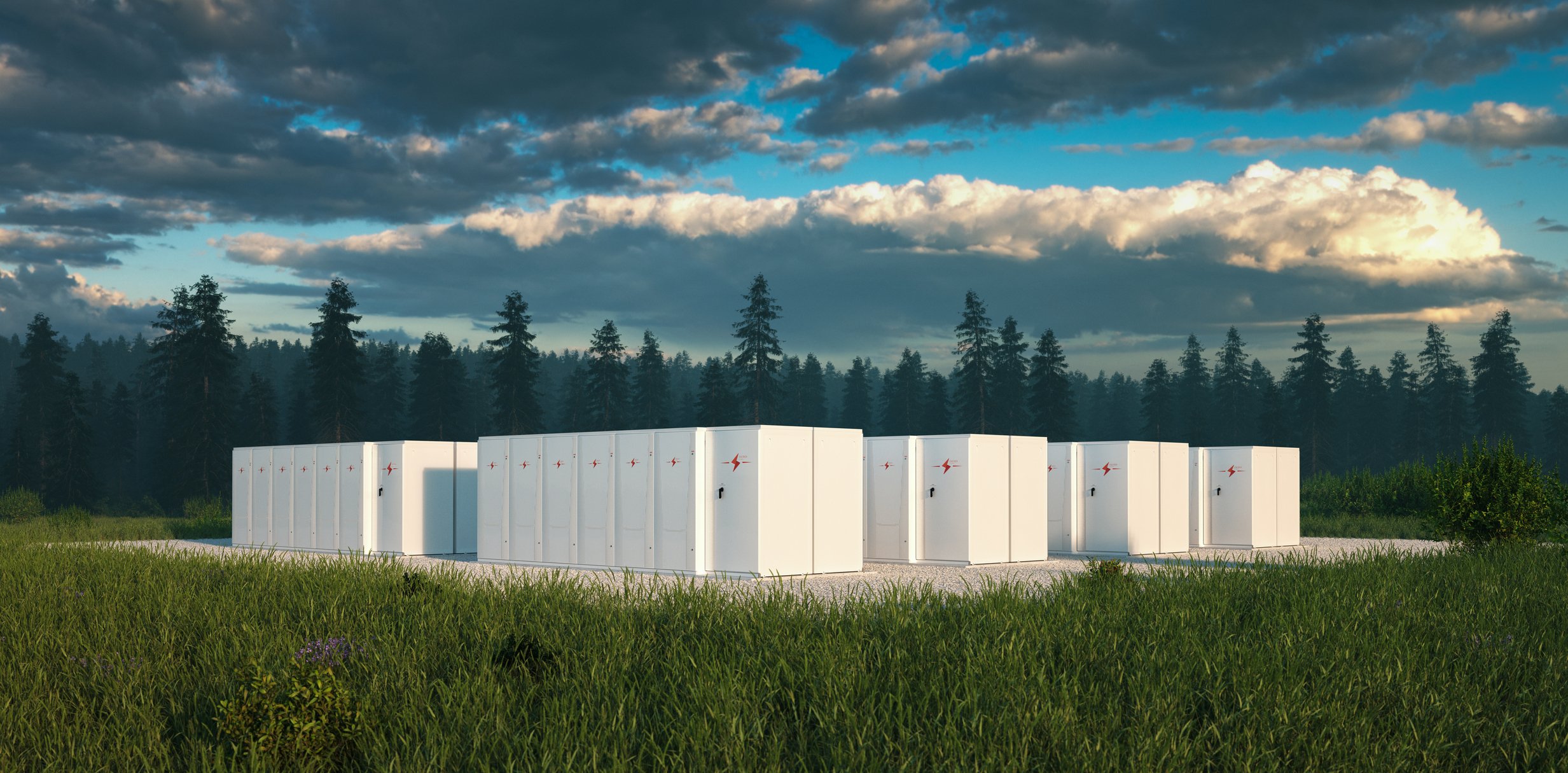 large-scale battery storage in a field with pine trees in background.