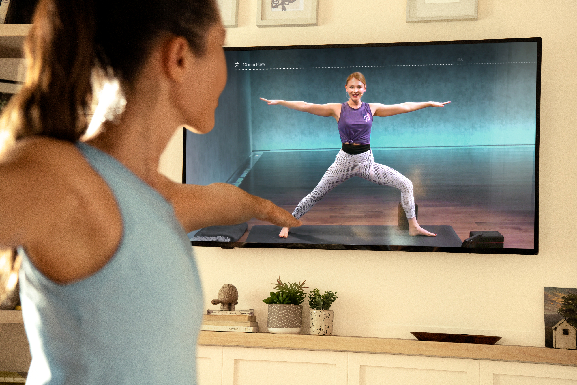 woman doing yoga using Peloton digital app on TV