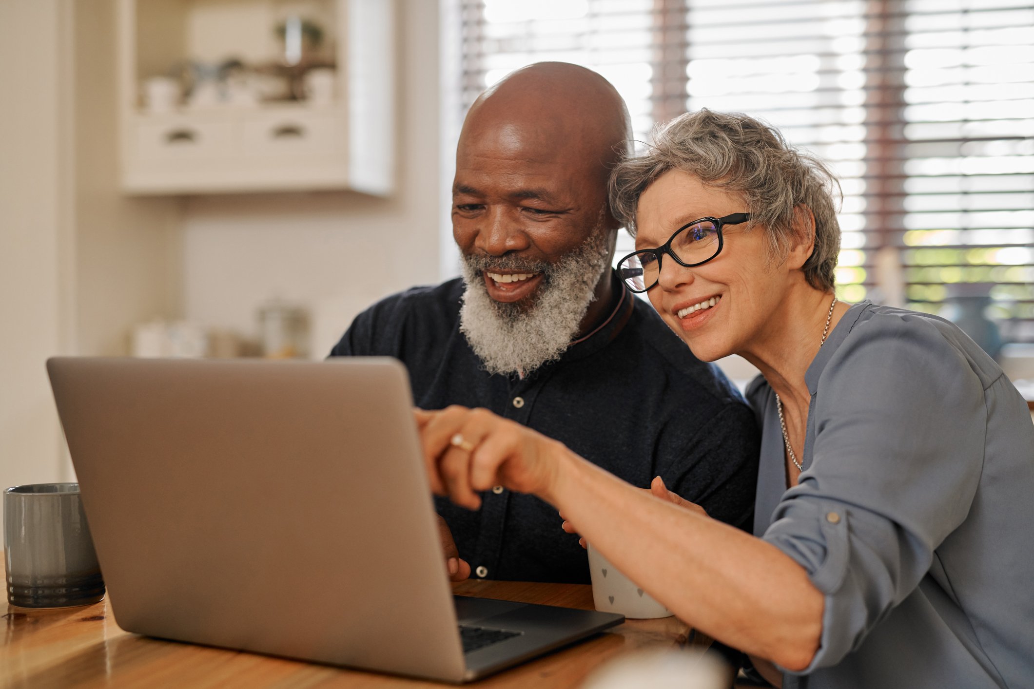 Two smiling people looking at a laptop.